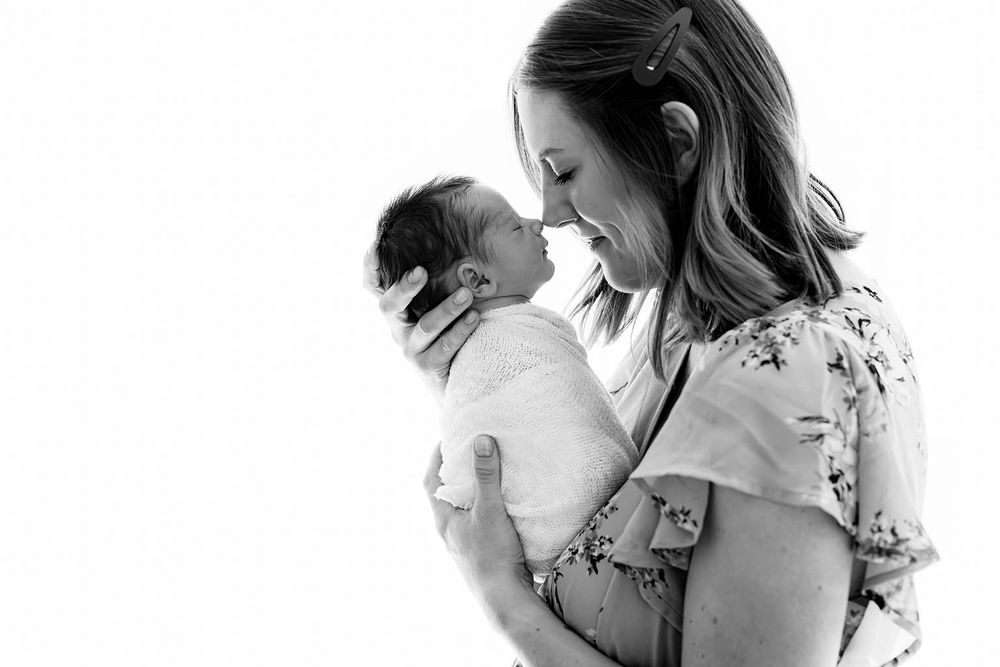 Black and white photo of mother tenderly holding and gazing at her newborn baby by Menifee newborn preemie photographer.