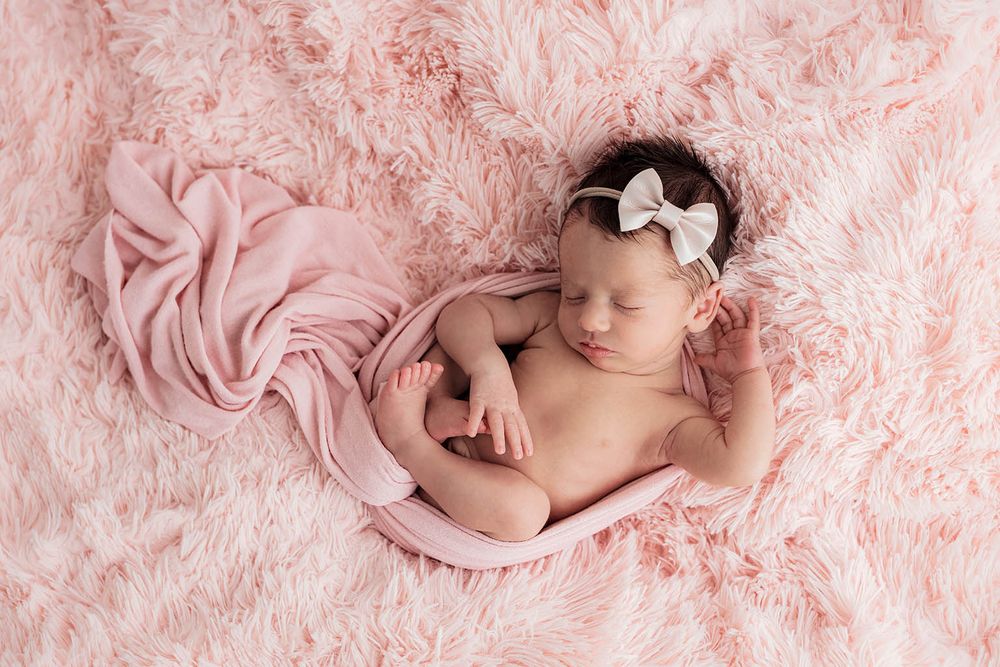 Peaceful newborn baby girl sleeping on pink fluffy blanket by Menifee newborn preemie photographer.