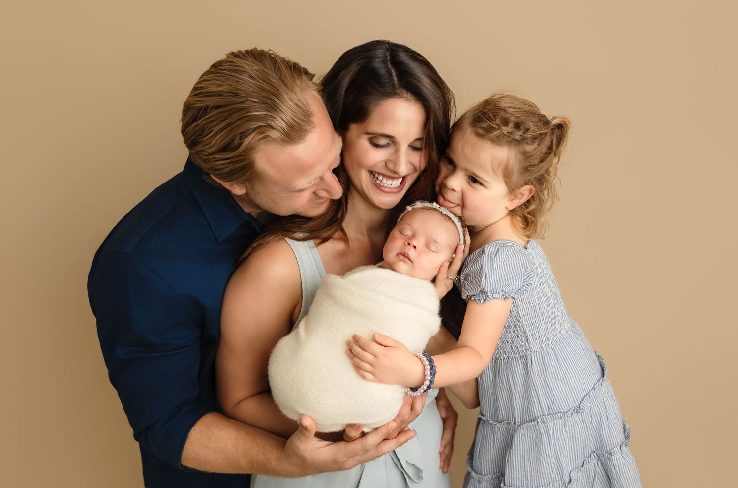 Gorgeous family of four enjoys a moment of connection and fun as mom cradles baby sister, captured by Charlottesville newborn photographer.