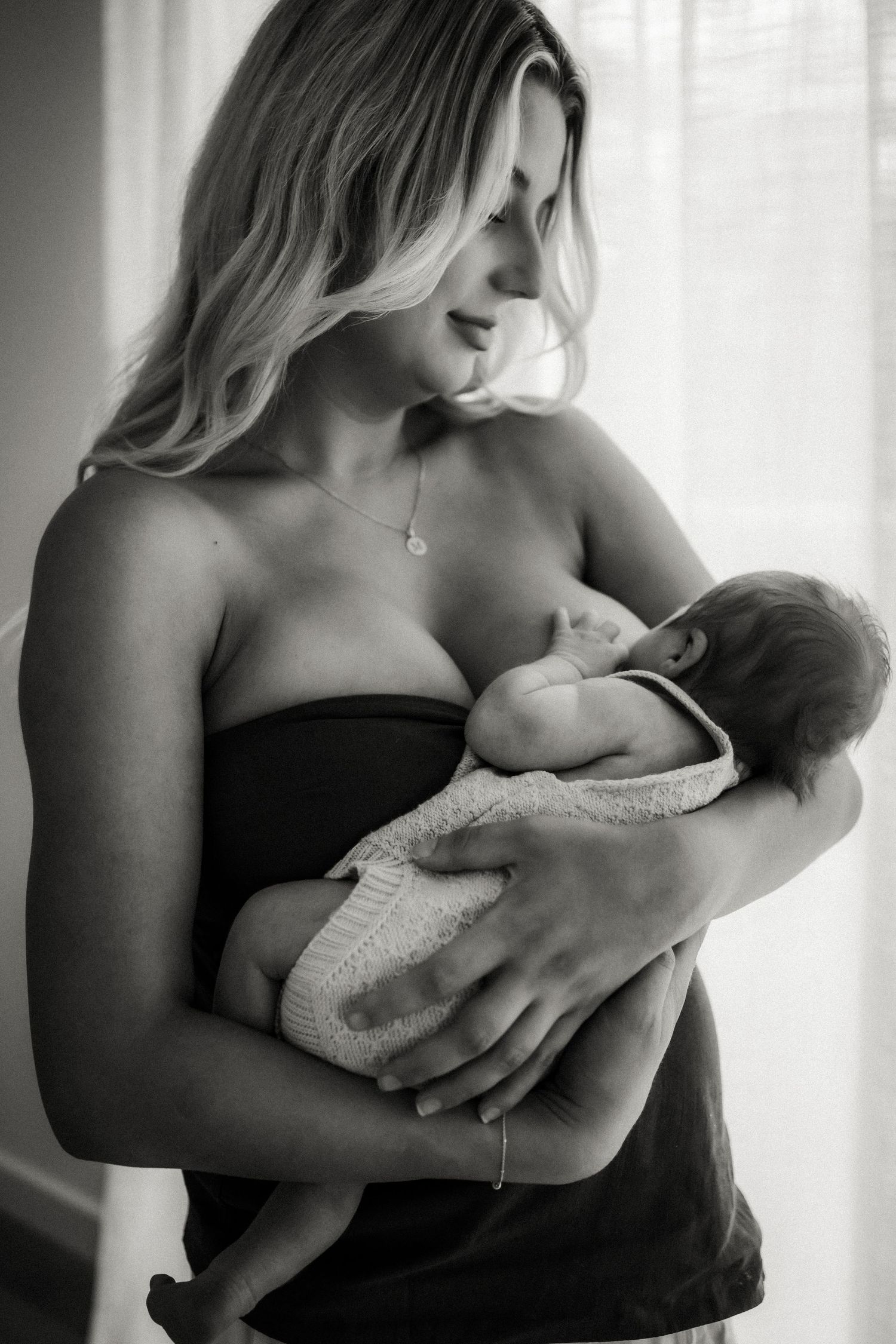 Black and white photo of a woman tenderly cradling a newborn baby in the Buxton, Victoria Studio