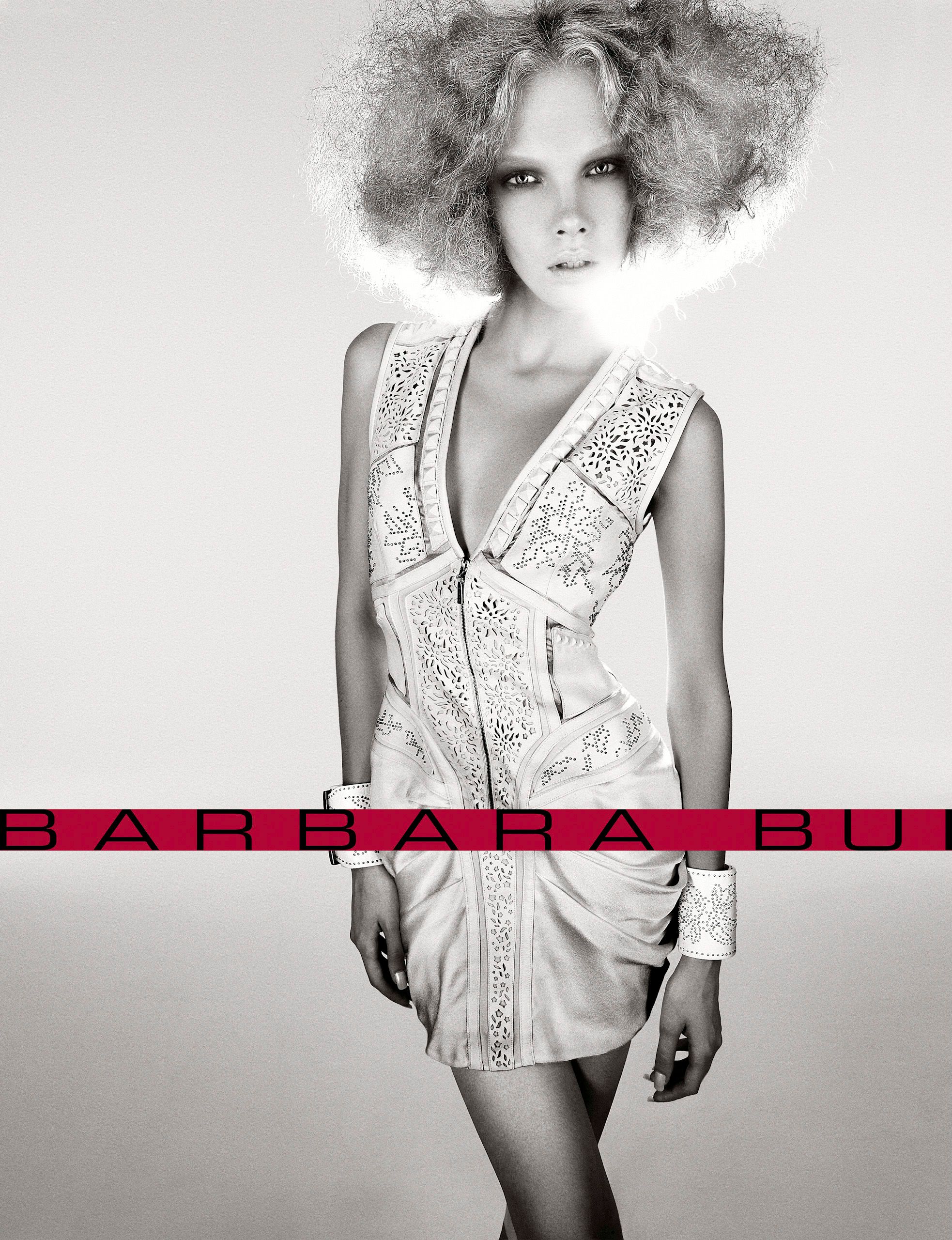 Barbara Bui fashion campaign featuring a model in a white lace mini dress with an afro hairstyle, black and white photo.