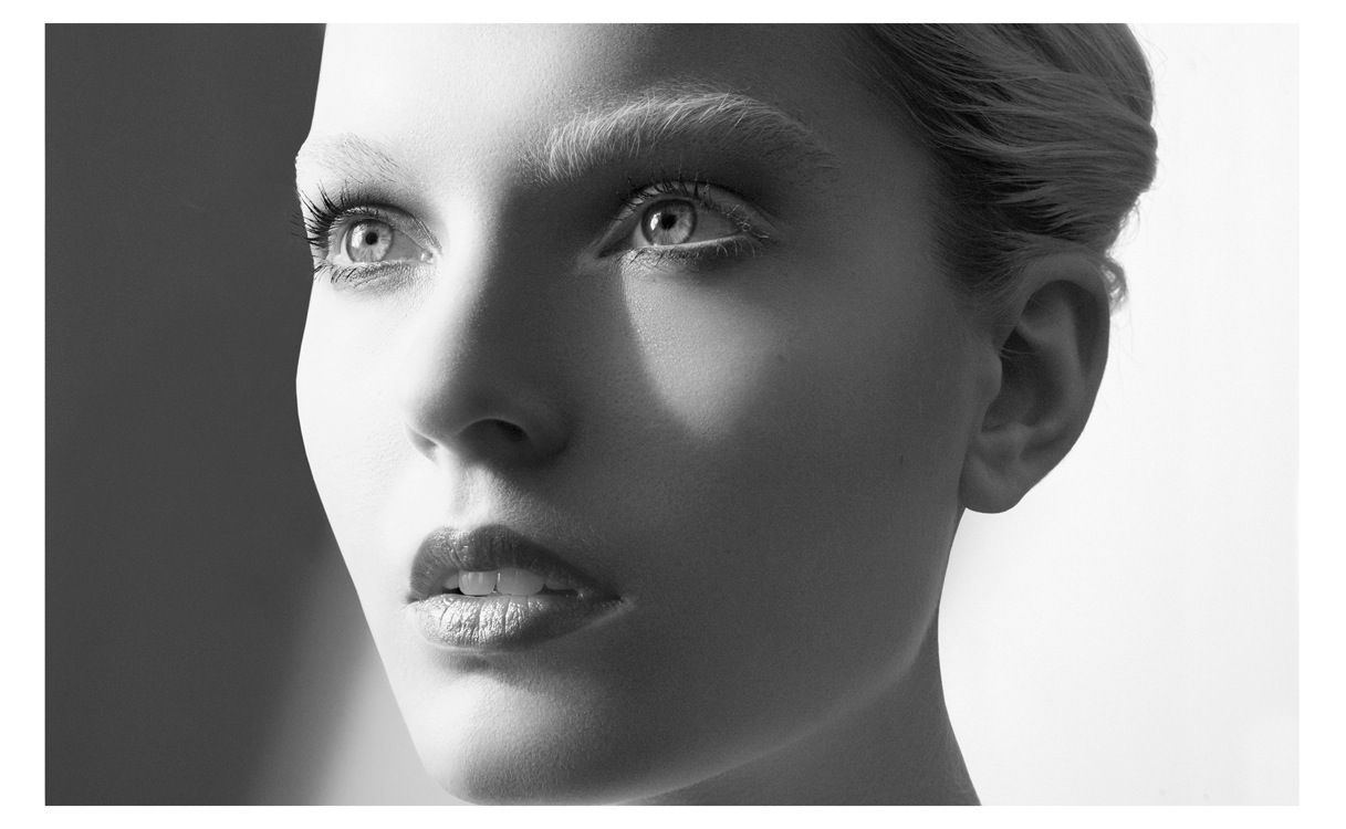 Black and white portrait of a young woman with elegant features, smooth skin, and a serene expression.