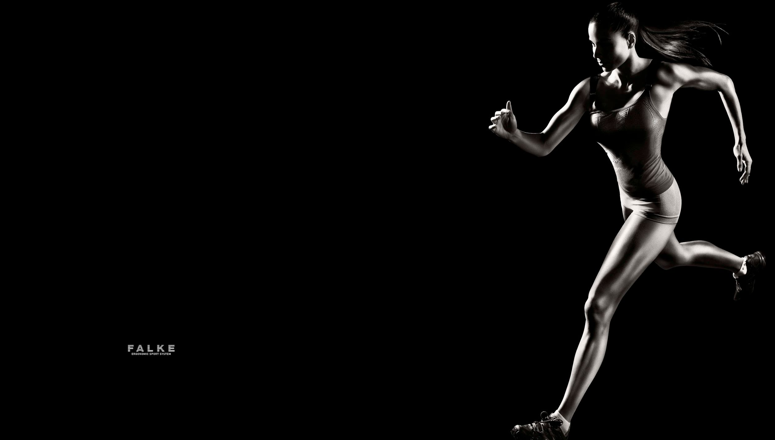 A female athlete sprints dynamically against a black background, showcasing lean muscle definition in a powerful running pose.