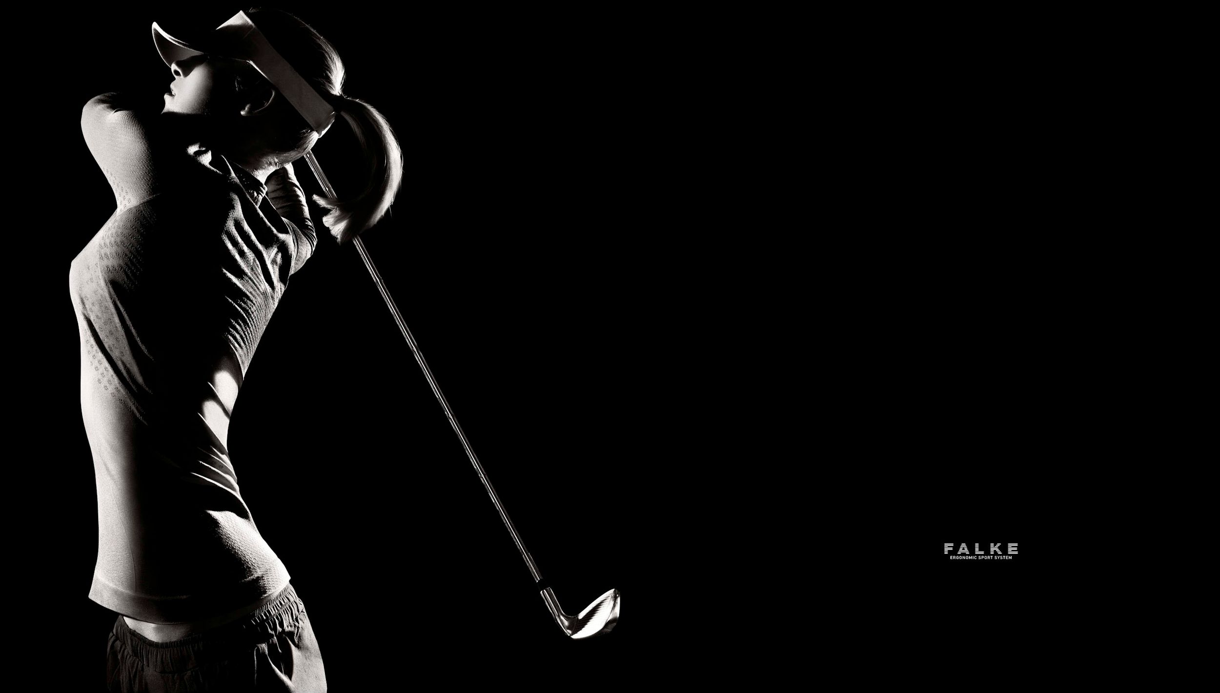 A dramatic black and white silhouette of a golfer completing a powerful swing against a dark background.