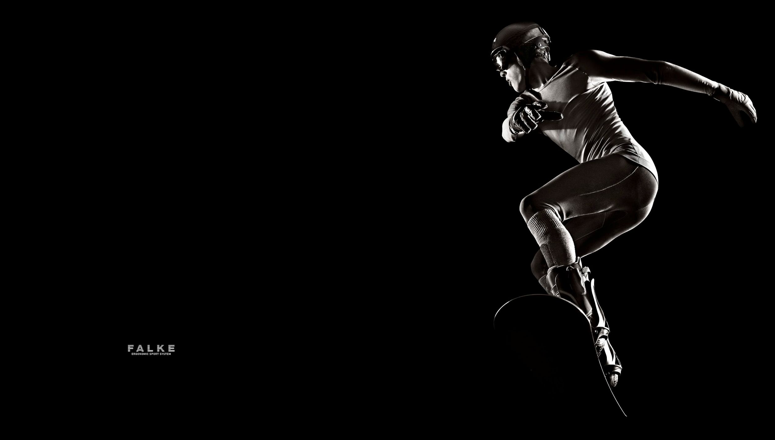 A dynamic dancer leaps gracefully against a stark black background in a dramatic black and white artistic photograph.