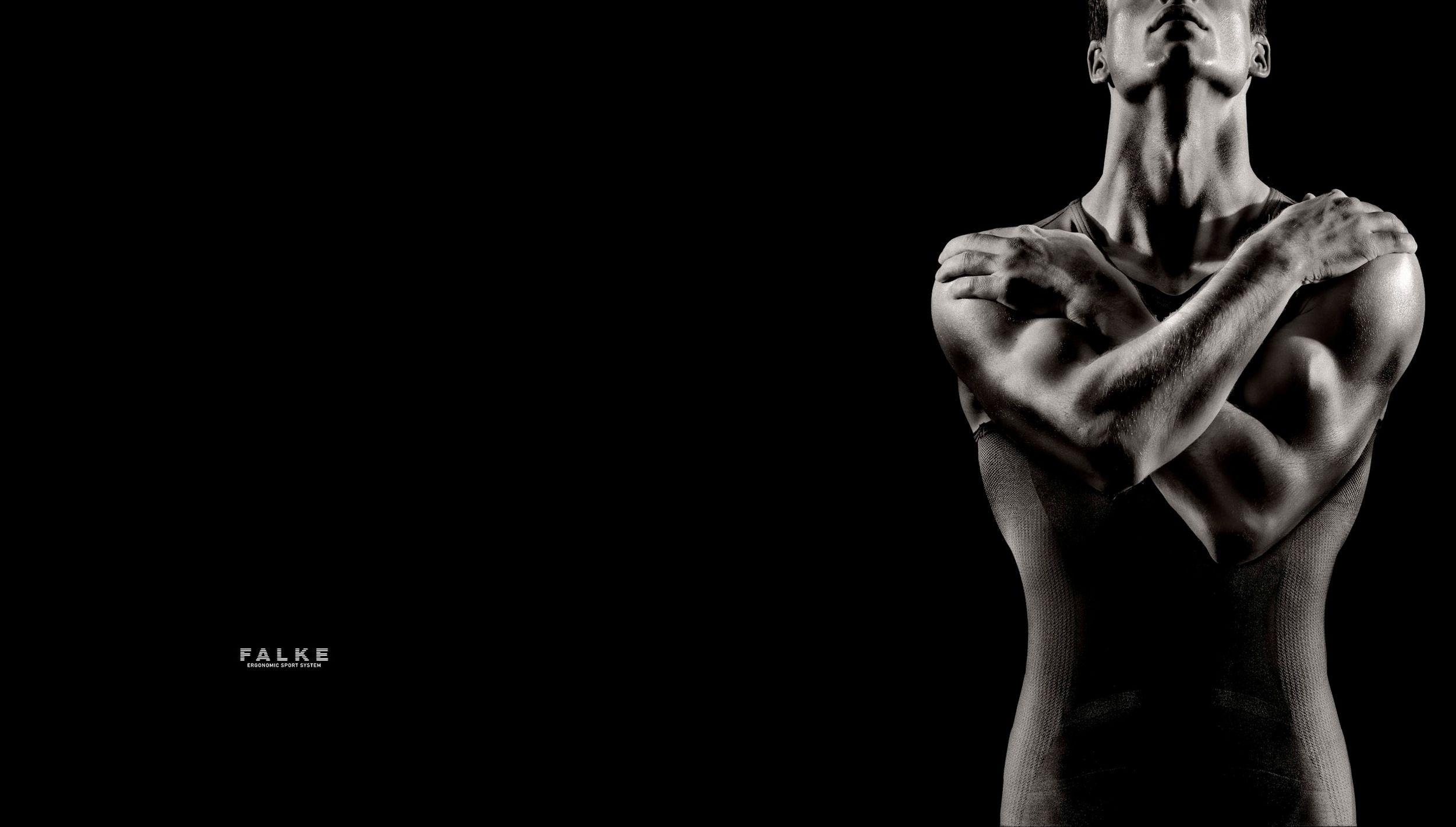 Muscular person with arms crossed over chest in dramatic black and white artistic photography.
