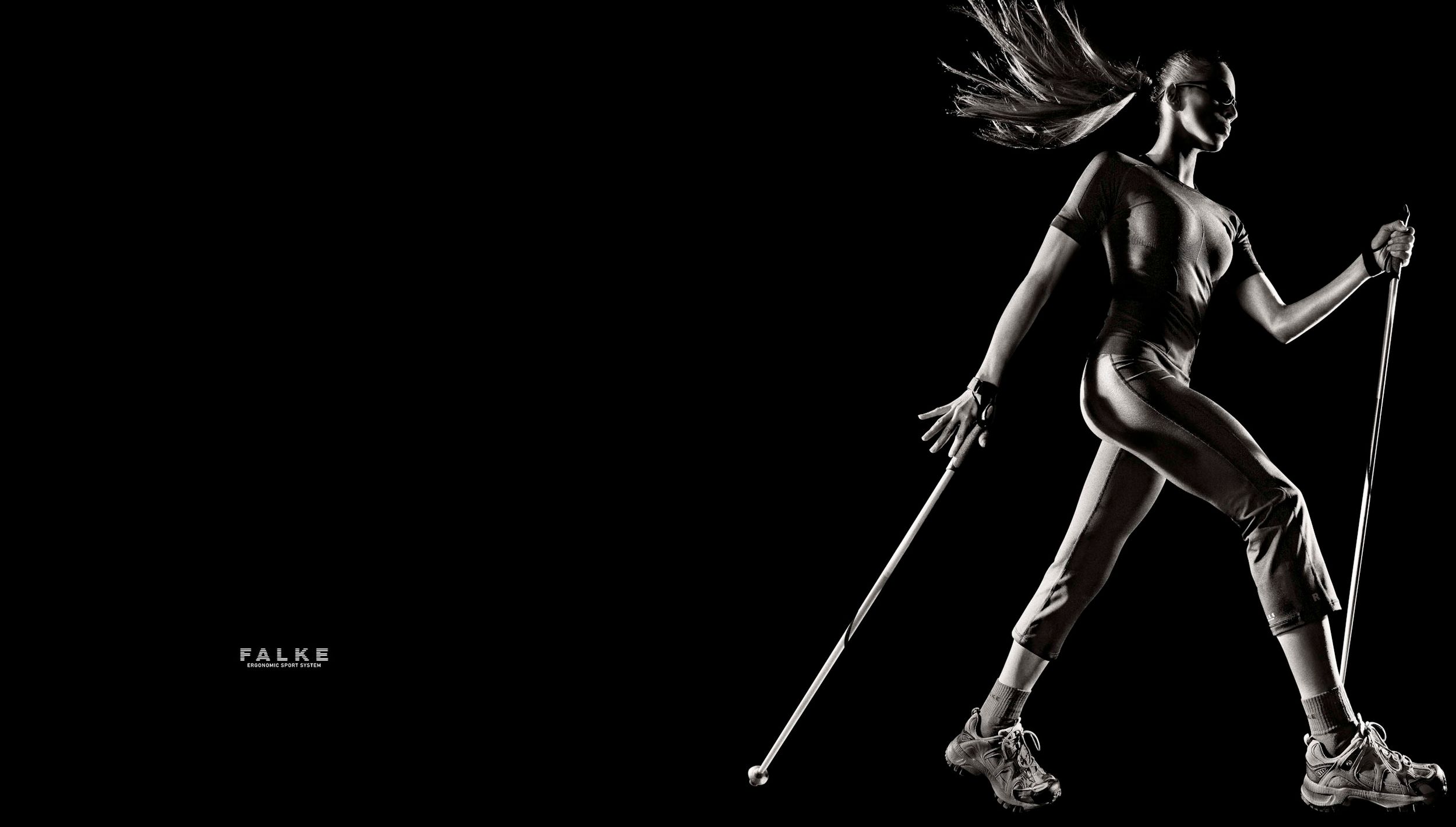 Athletic woman in dynamic Nordic walking pose against black background, holding poles mid-stride.