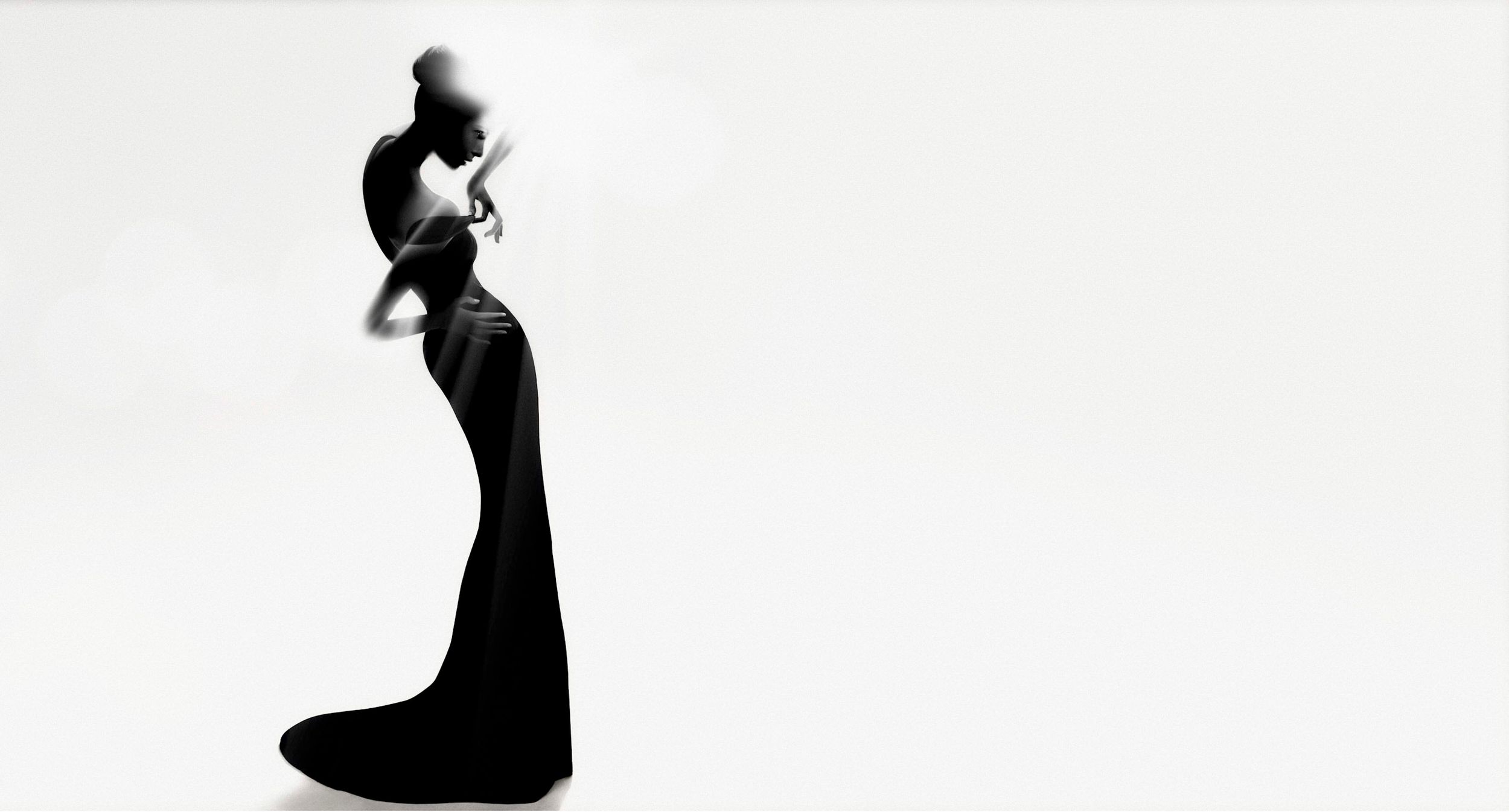 Elegant woman in a black evening gown silhouette against white background, fashion photography.