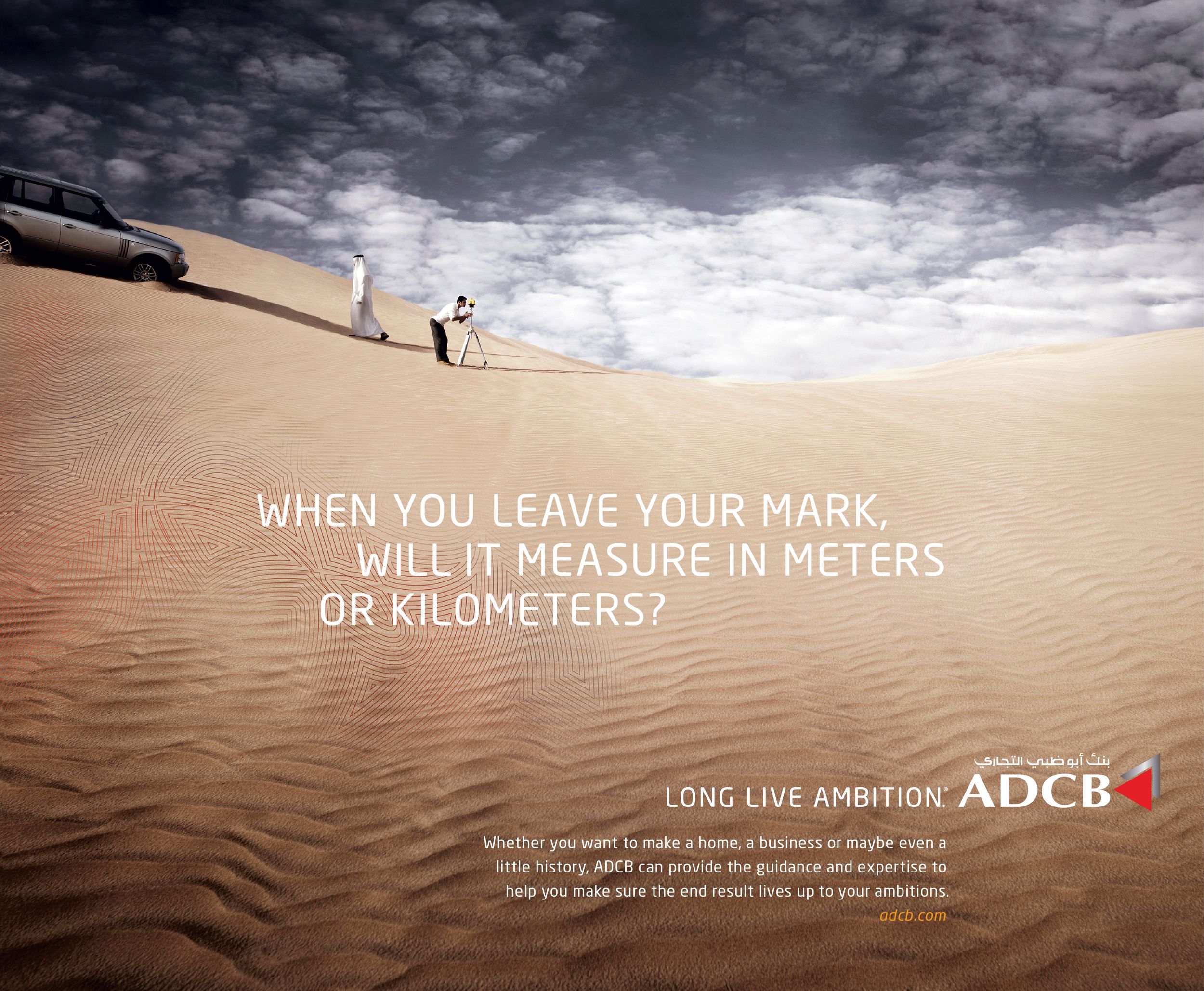 ADCB bank ad featuring two figures on a vast sand dune with the tagline about measuring ambition in meters or kilometers.