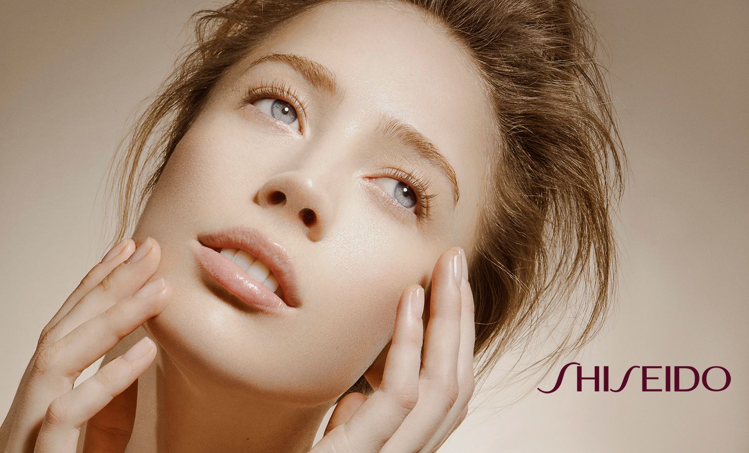 A woman with flawless skin gently touches her face in a Shiseido beauty advertisement.