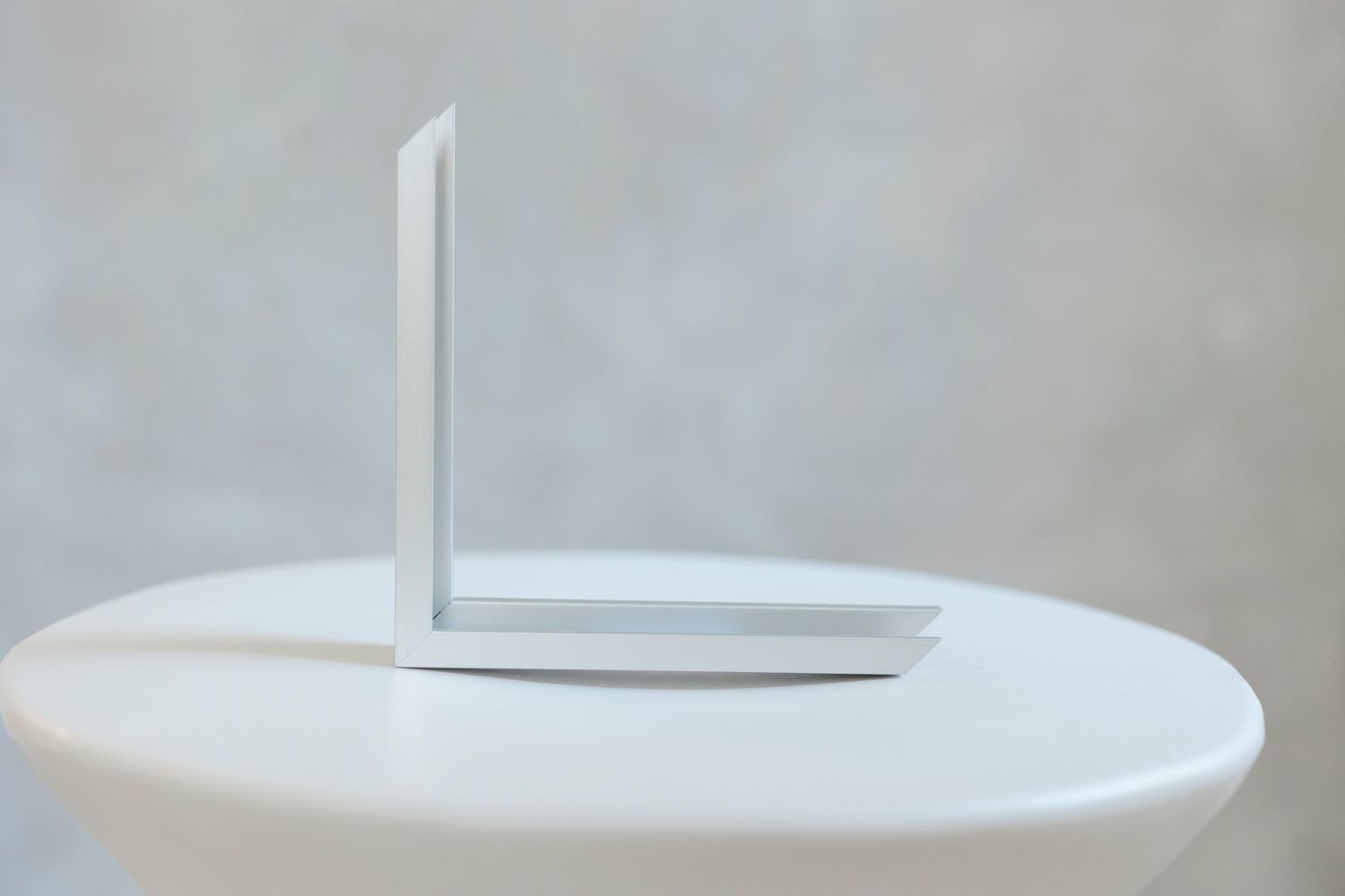 White Wi-Fi router with two antennas on a round white table against a gray background.