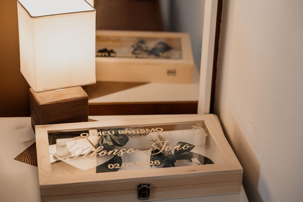 Wooden baptism keepsake box with acrylic lid and personalized name engraving displayed on a bedside table next to a lamp.