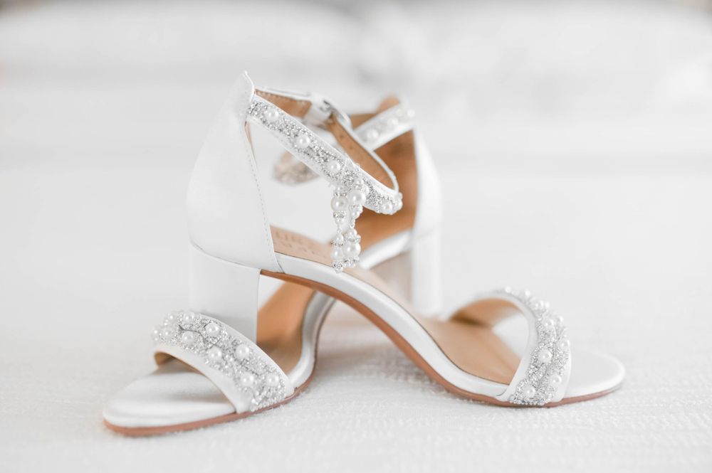White beaded bridal sandals with ankle straps on a light background.