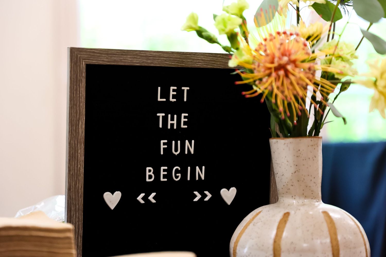 A letterboard sign reading 'Let the fun begin' with hearts and flowers in the decor.