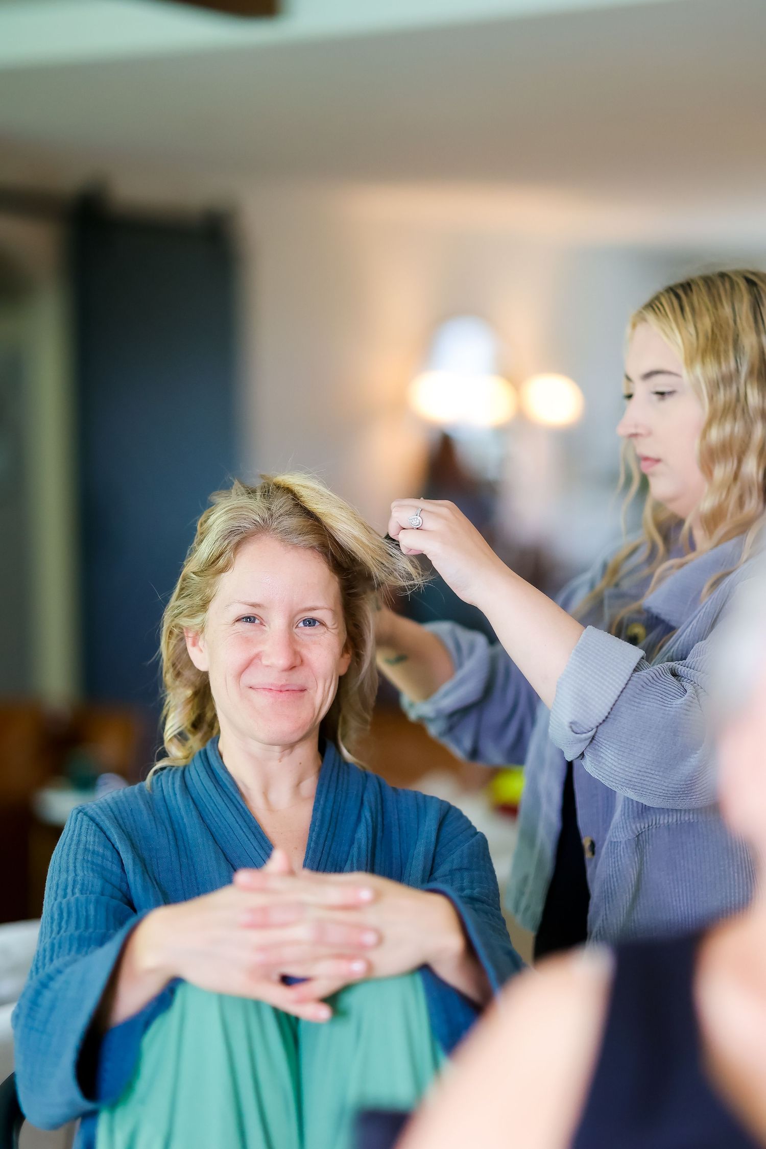 A stylist works on arranging hair during wedding preparations in a warmly lit room.