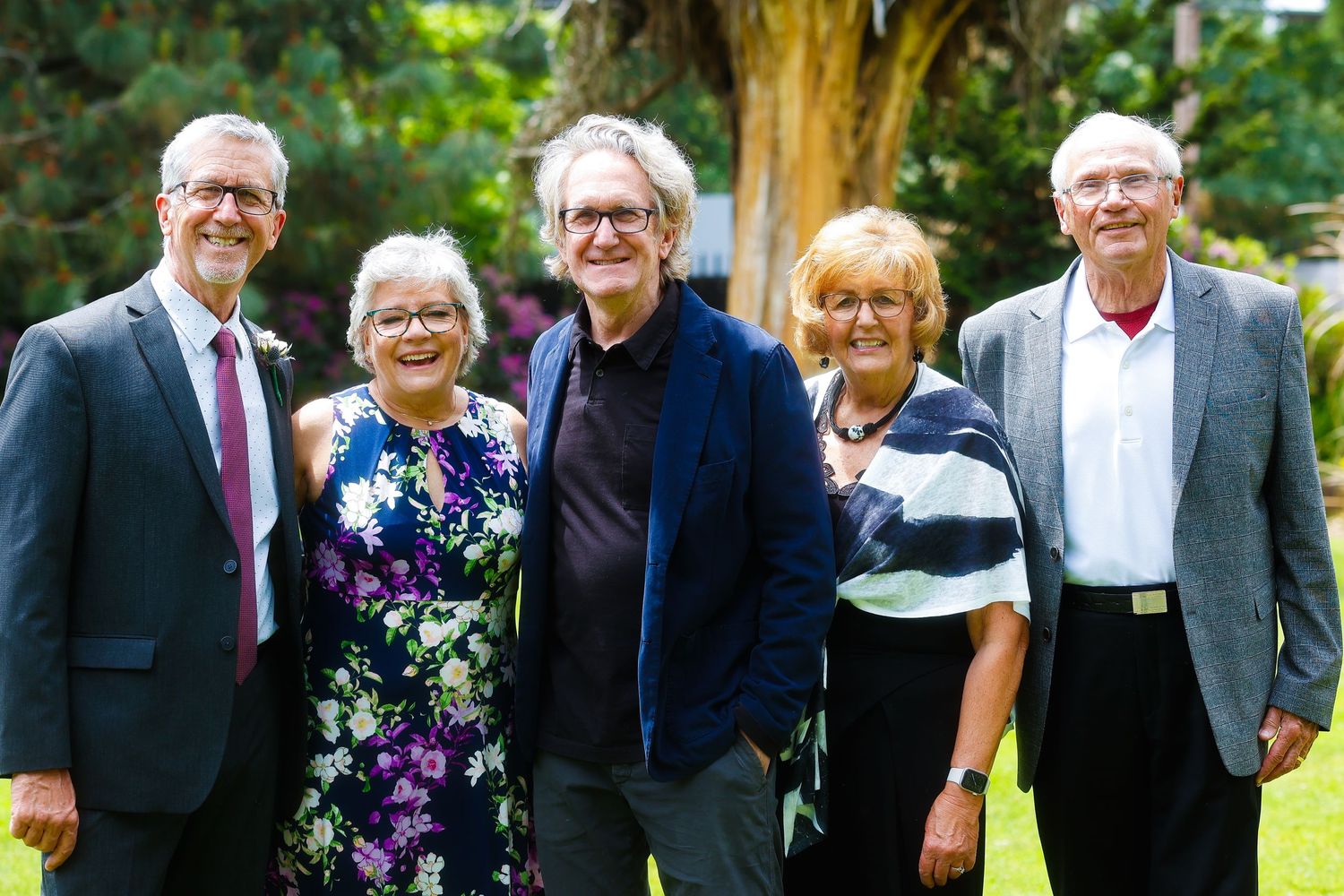 A group photo of formally dressed people standing together outdoors.