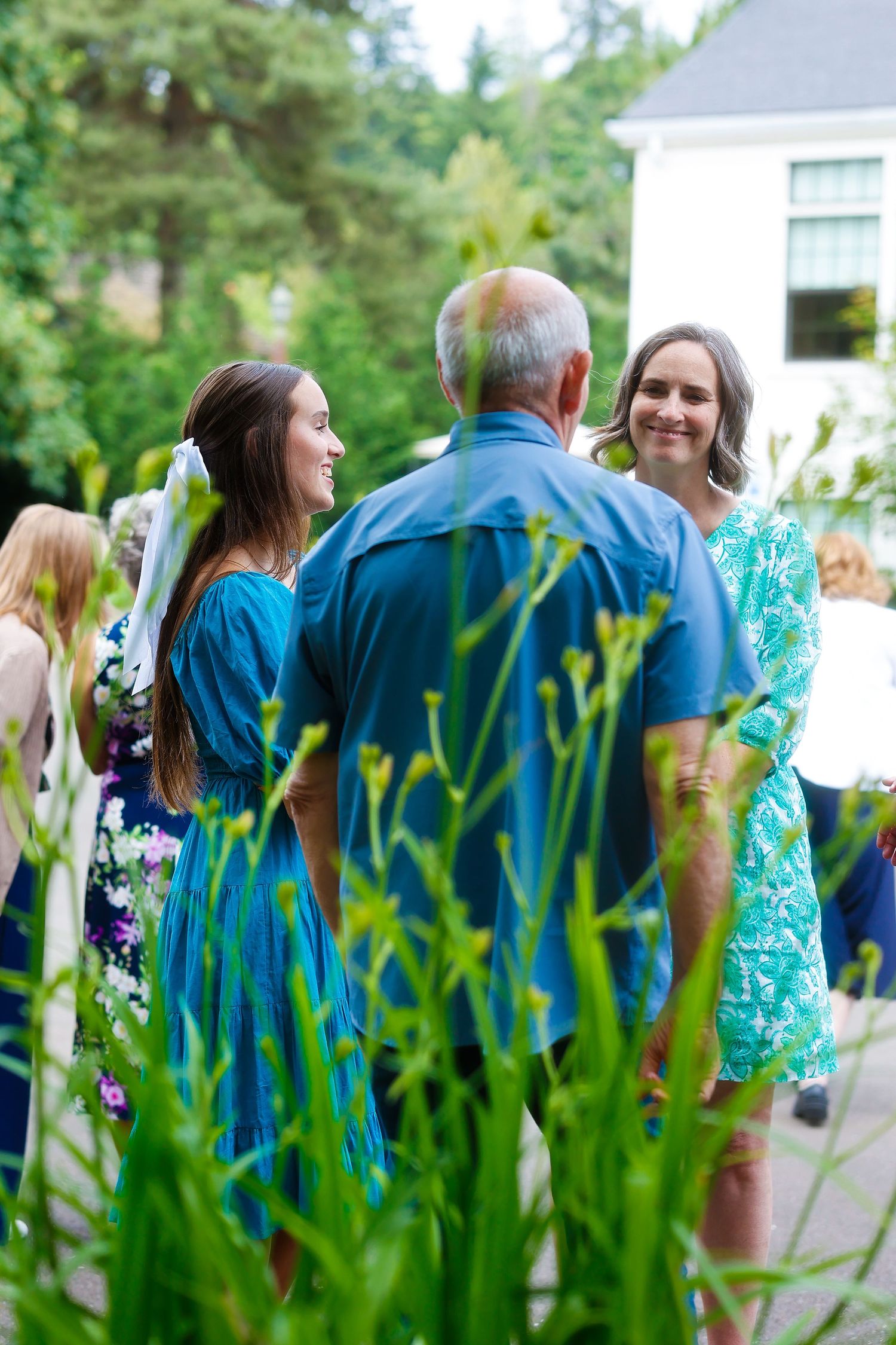 People chatting at an outdoor gathering with tall grass in the foreground.