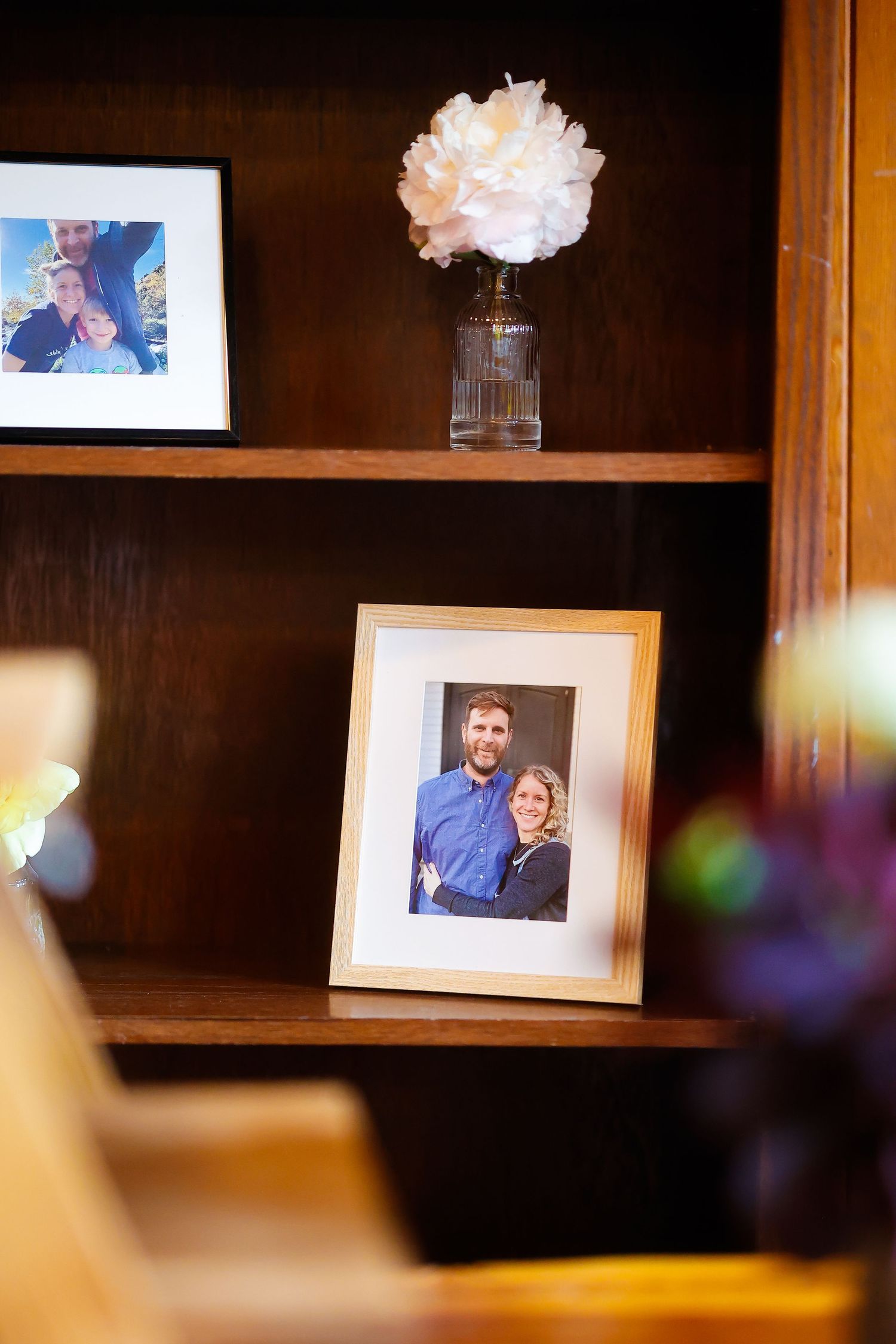 Framed photo and flower vase displayed on wooden shelf at wedding venue.
