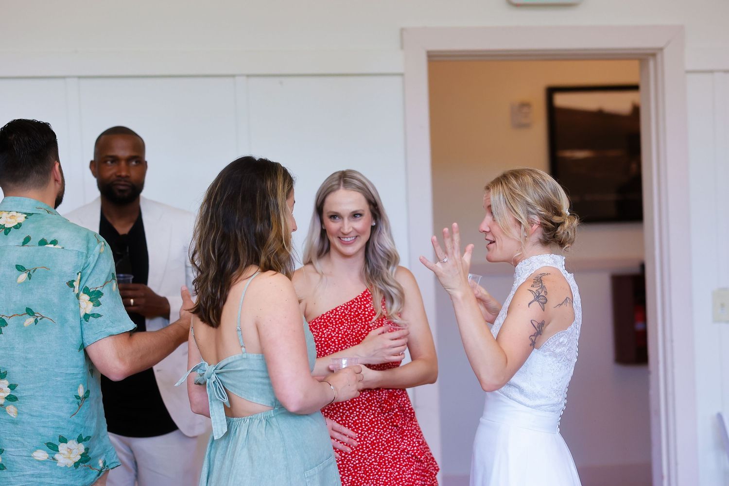 Wedding reception gathering with guests in colorful attire mingling indoors.