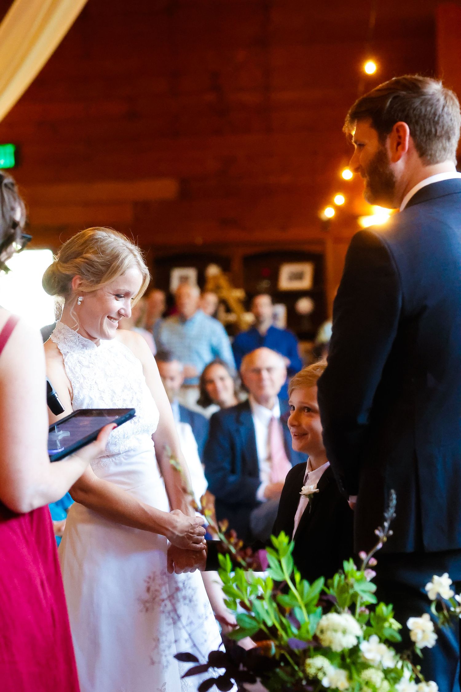 Indoor wedding ceremony with couple exchanging vows in front of gathered guests.