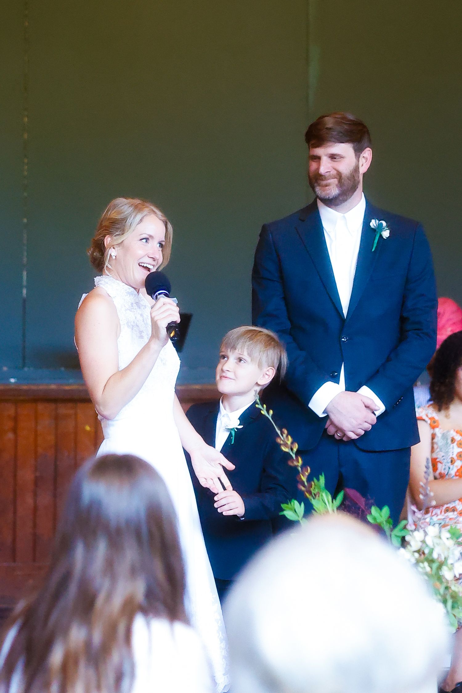 Wedding couple sharing a joyful moment during ceremony with young attendant nearby.