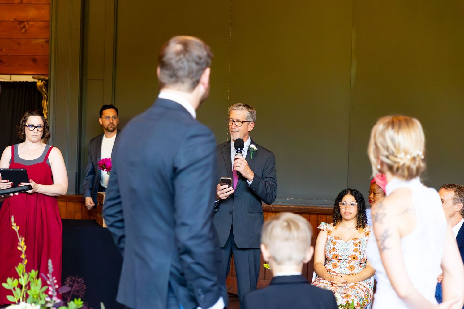 Wedding ceremony in progress with officiant speaking to couple in formal attire.