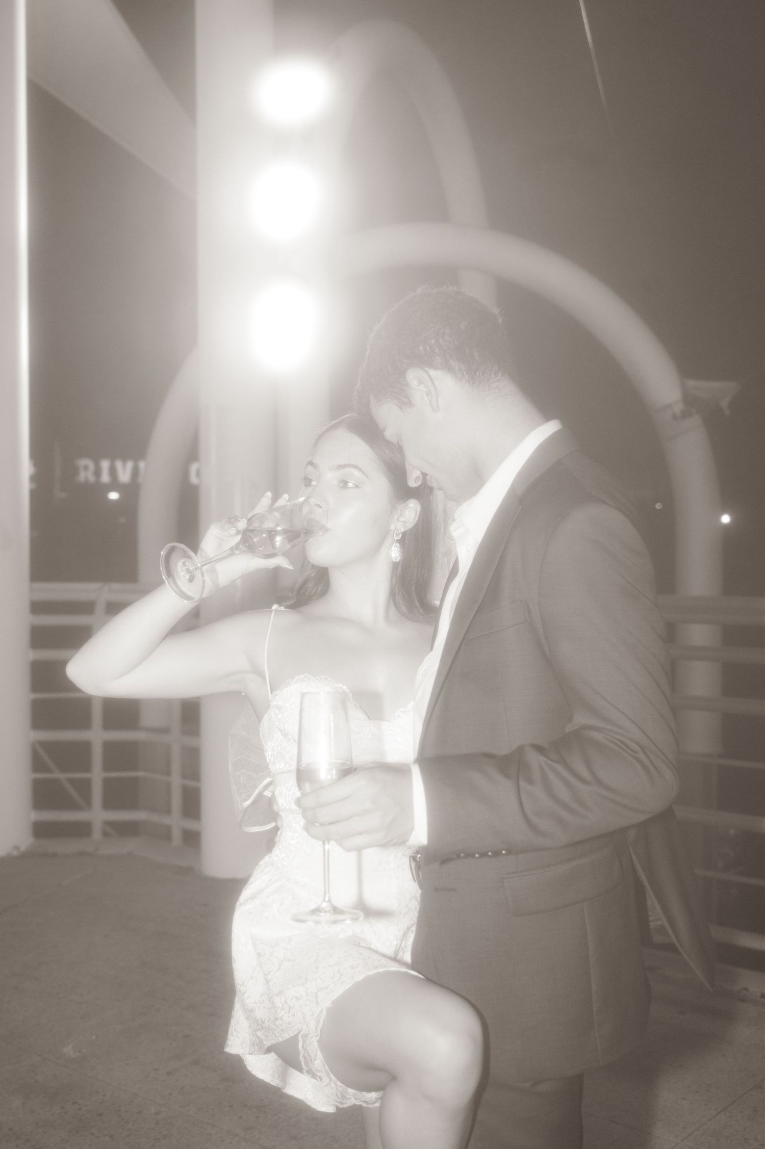 A couple in formal attire shares drinks together during an evening celebration.