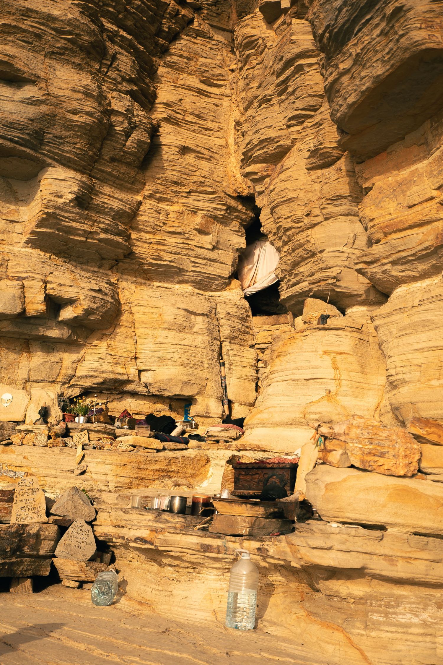 Ancient cave dwelling with carved shelves and ledges in golden sandstone walls.