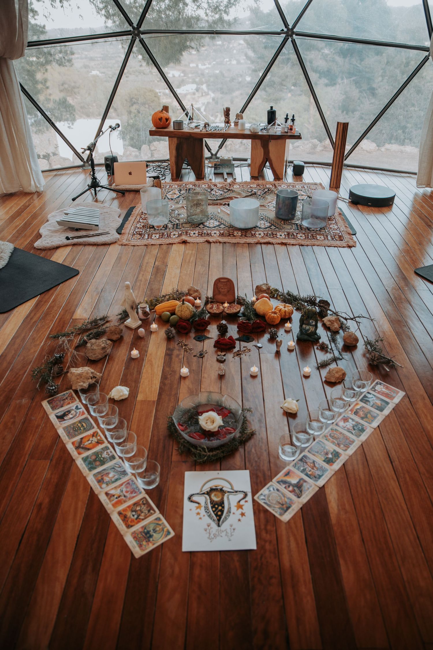 Bohemian style altar setup on wooden deck with candles and decorative elements in geometric dome.