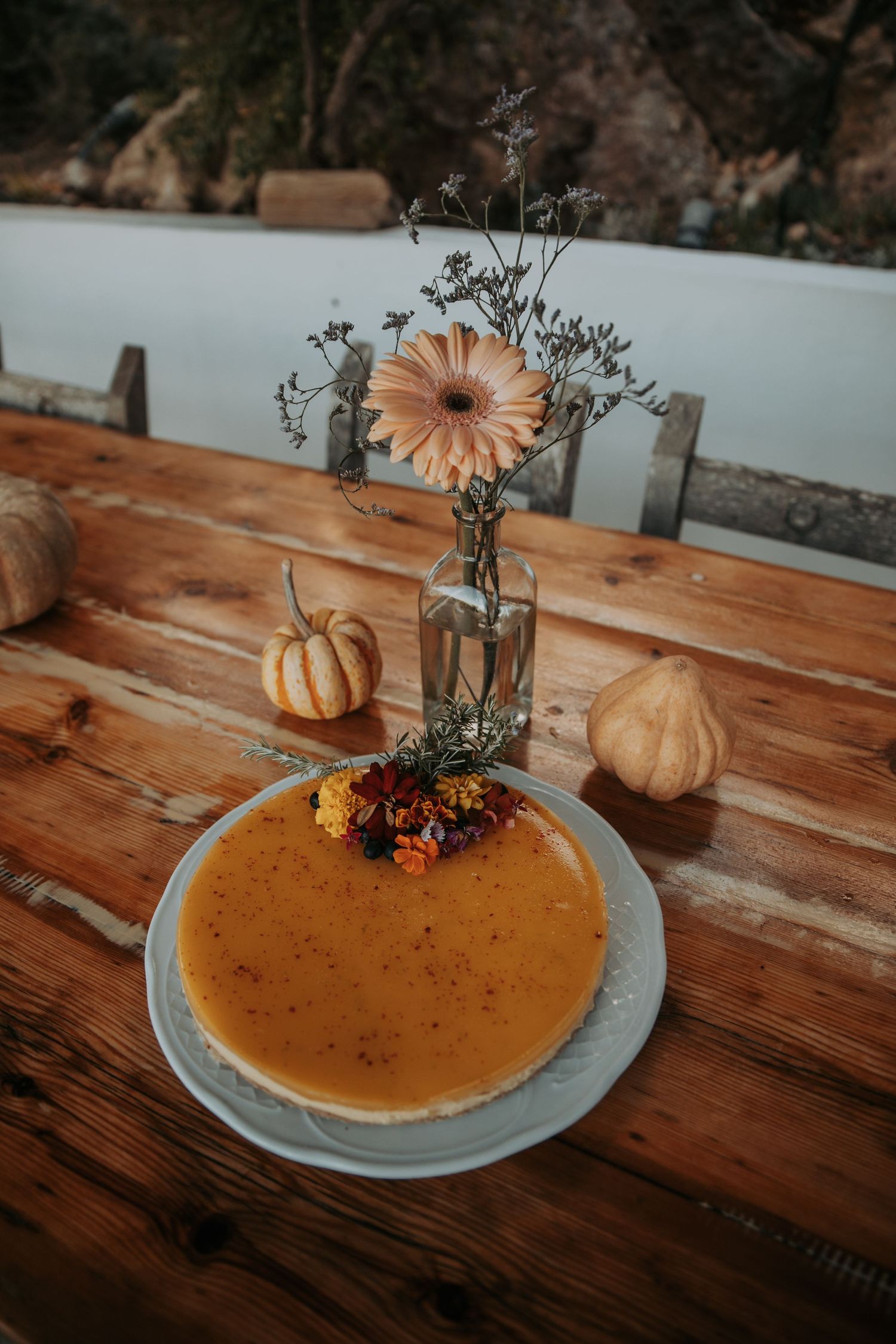 Pumpkin pie on a wooden table decorated with fall flowers and small decorative pumpkins.