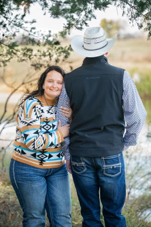 A couple in matching southwestern outfits poses against a natural backdrop.