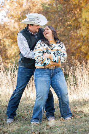 A playful outdoor portrait featuring southwestern style clothing and a white cowboy hat.
