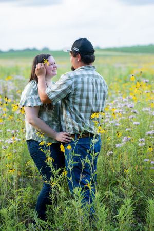 Couple shares romantic moment among yellow wildflowers in rural field.