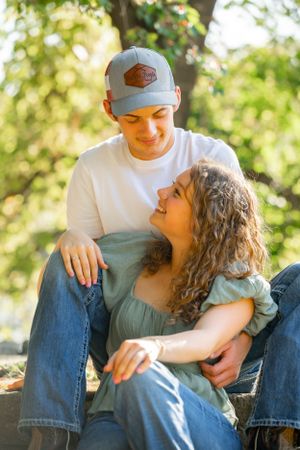 A tender moment shared while sitting outdoors in dappled sunlight.