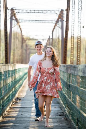 A couple shares a joyful moment on a rustic wooden bridge.