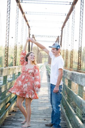 Dancing and twirling on an old iron bridge during a sunny afternoon.