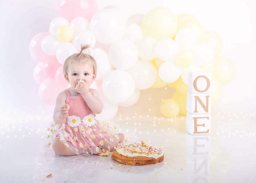 Elegant first birthday setup featuring a decorated cake and soft pastel balloon backdrop.