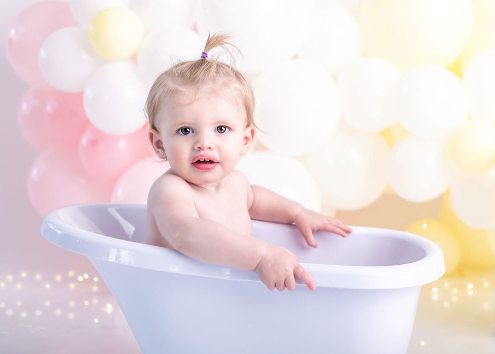 Dreamy bath photography setup featuring a white clawfoot tub against pastel balloons.