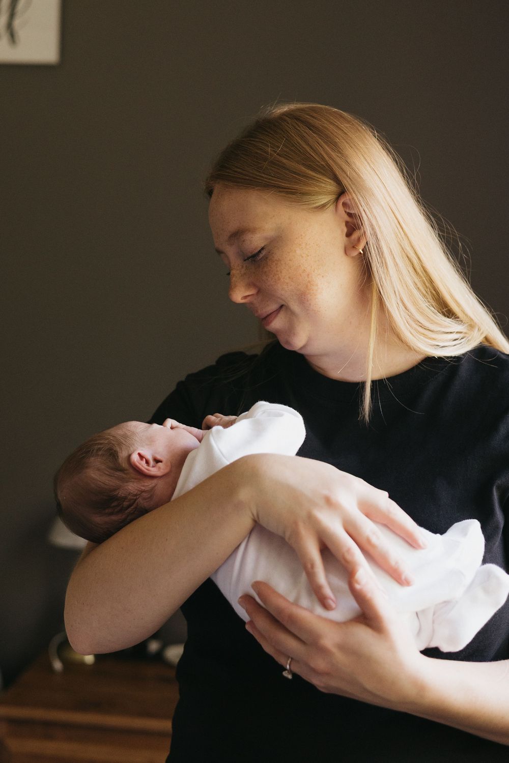 A series of intimate newborn photography moments captured against a dark background in warm lighting.