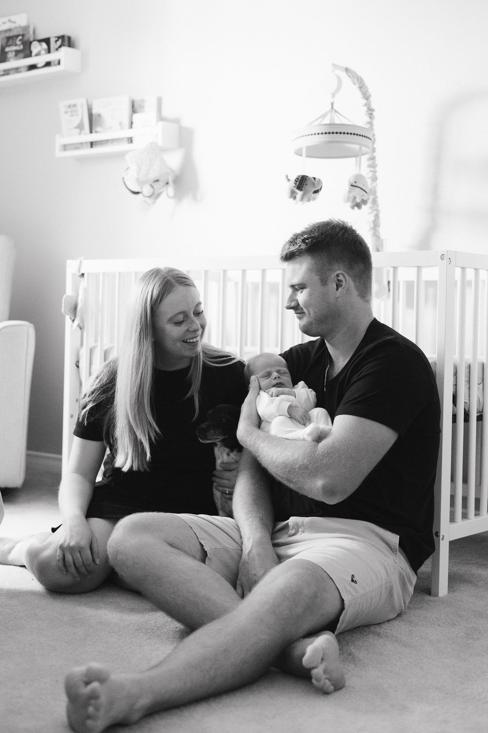 A family relaxes together on the nursery room floor in a series of black and white photos.