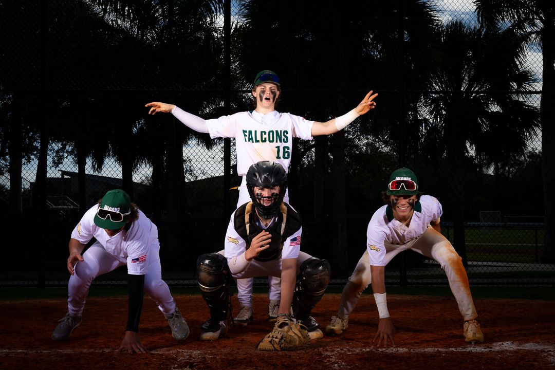 Baseball players pose creatively in a choreographed team photo showing off fielding stances on a dirt infield.