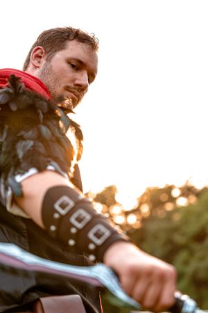 Person in black armor and red garments photographed from below against sunset sky during outdoor LARP session.