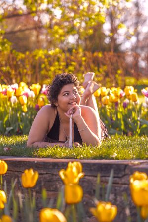 Someone relaxes in a garden surrounded by blooming yellow tulips during golden hour.