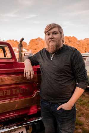 A red vintage pickup truck with text reading 'RED TRC' parked against an orange-tinted autumn background.