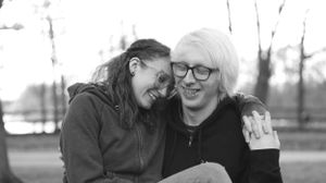 A happy couple embraces and laughs together outdoors in a black and white photograph.