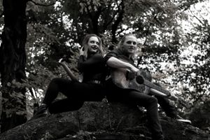 Two armed figures crouch in defensive positions on a rocky outcrop in a black and white photograph.
