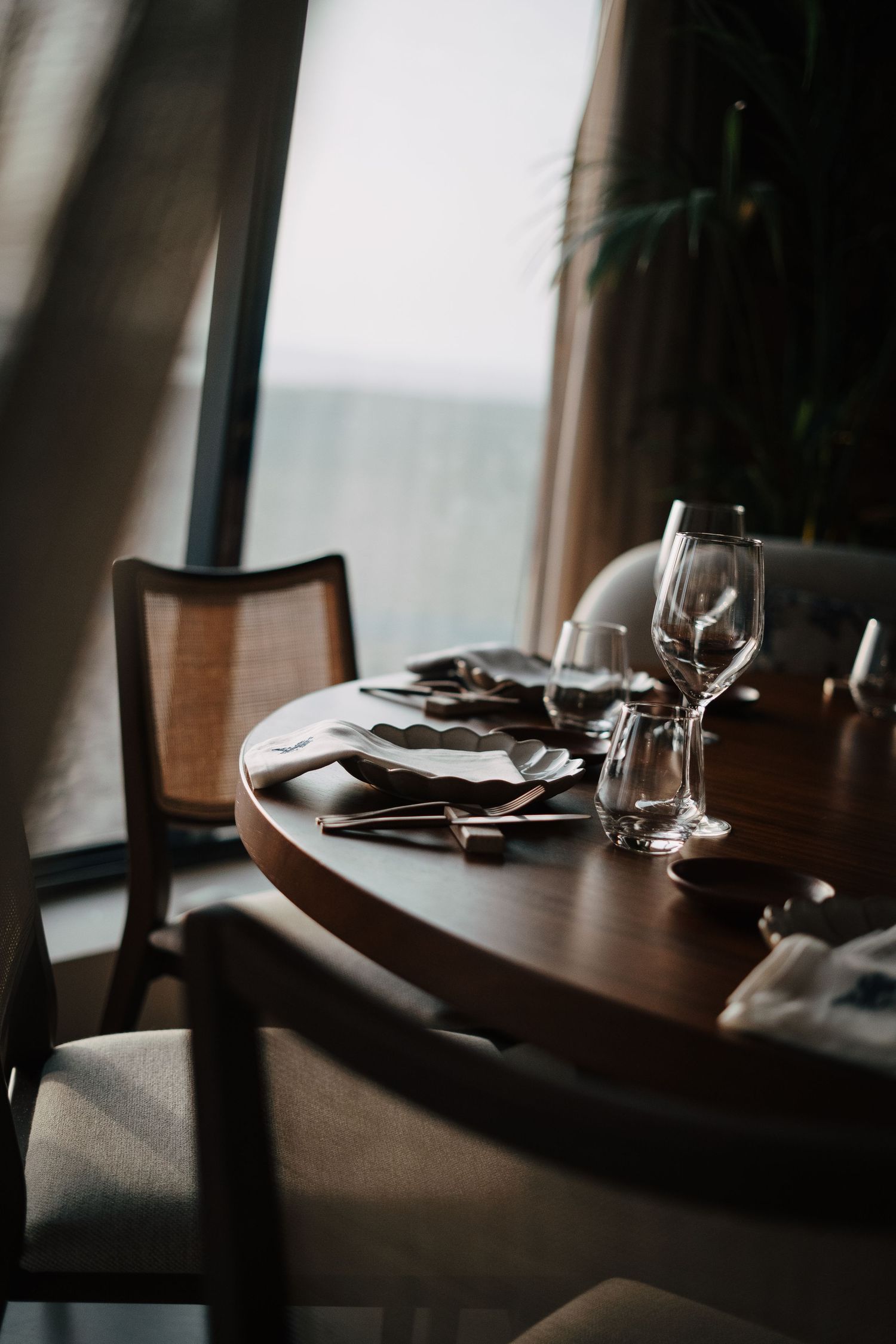 Place settings at an upscale restaurant with wine glasses in dramatic lighting.