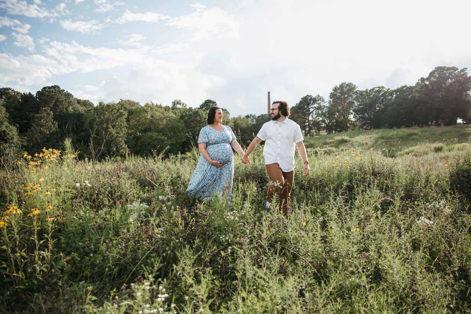 Couple walking through wildflower field on sunny summer day.
