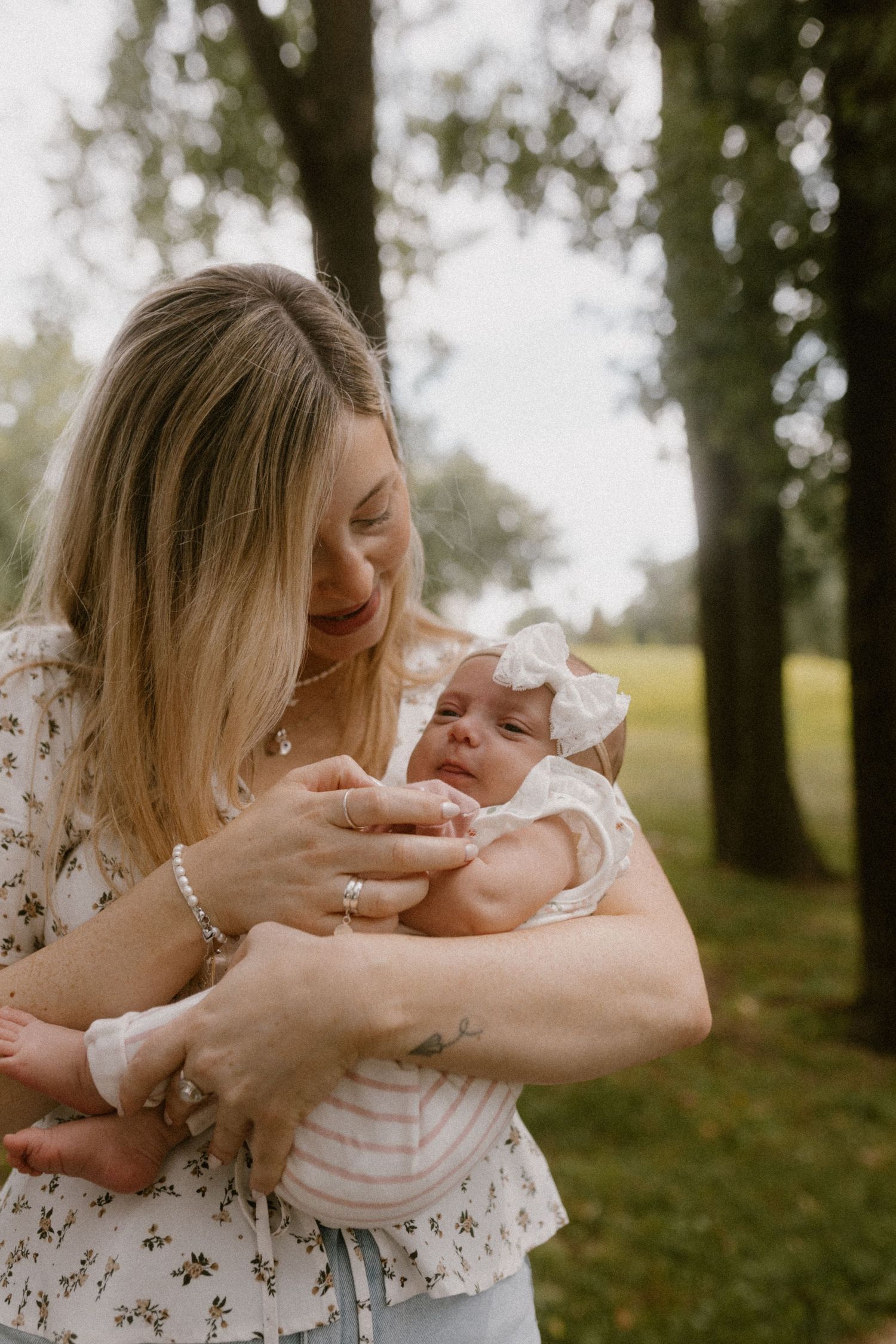 Gentle moment between parent and baby outdoors in a peaceful park setting.