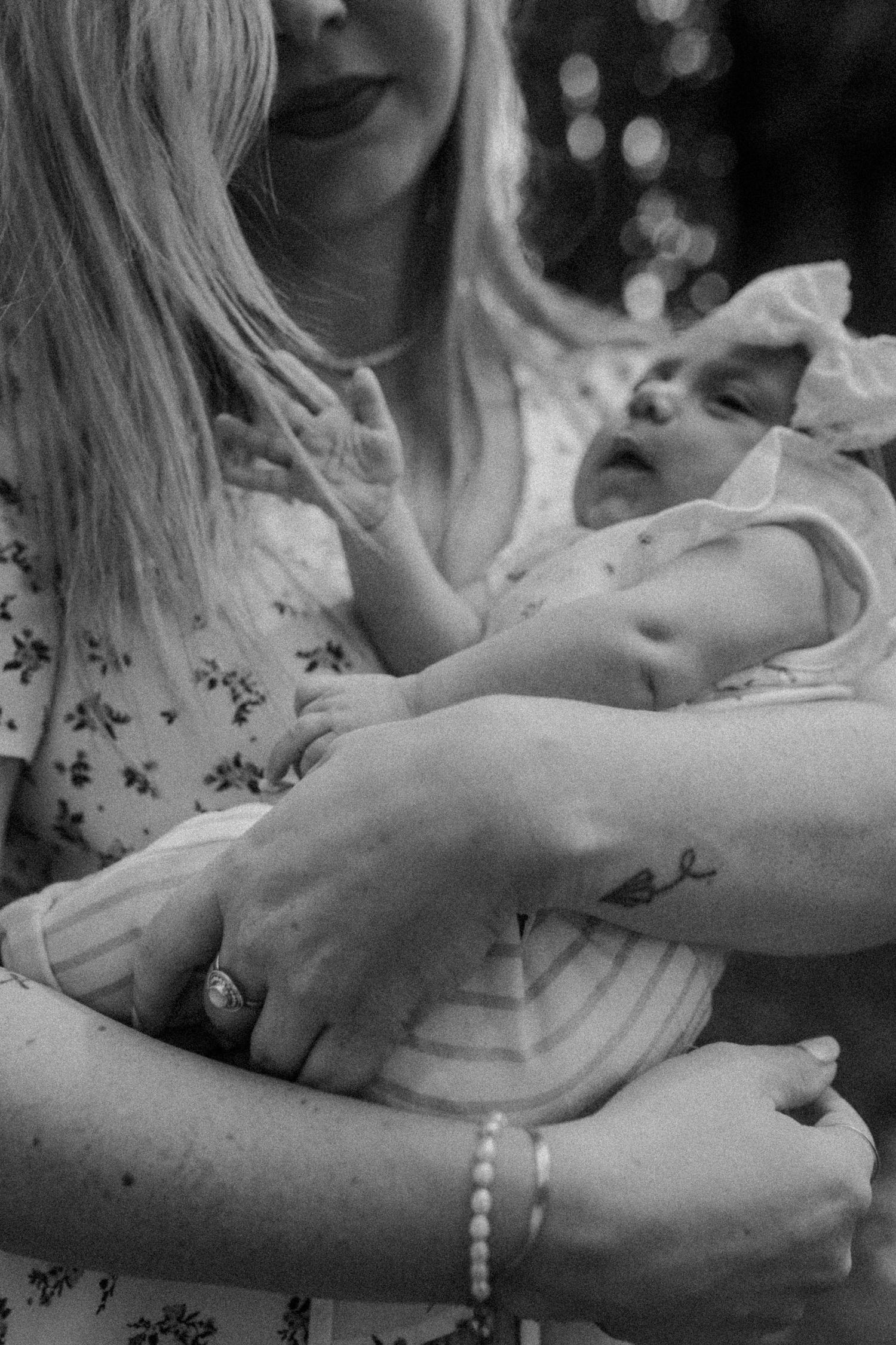 Black and white intimate portrait of a parent cradling a small infant.